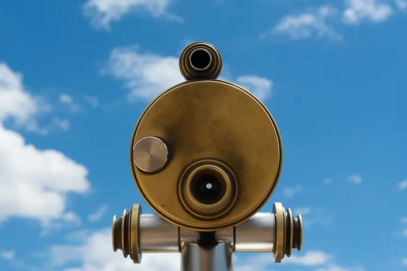 A close-up of a golden telescope against a clear blue sky, perfect for celestial observation