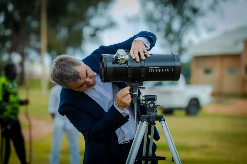 Adult man using a telescope outdoors during the day, engaged in astronomy