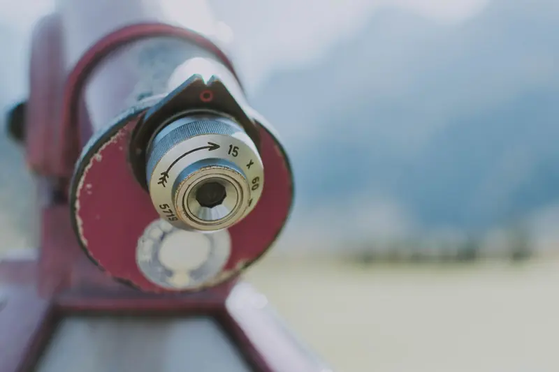 Detailed close-up of an outdoor telescope lens with a blurred natural background