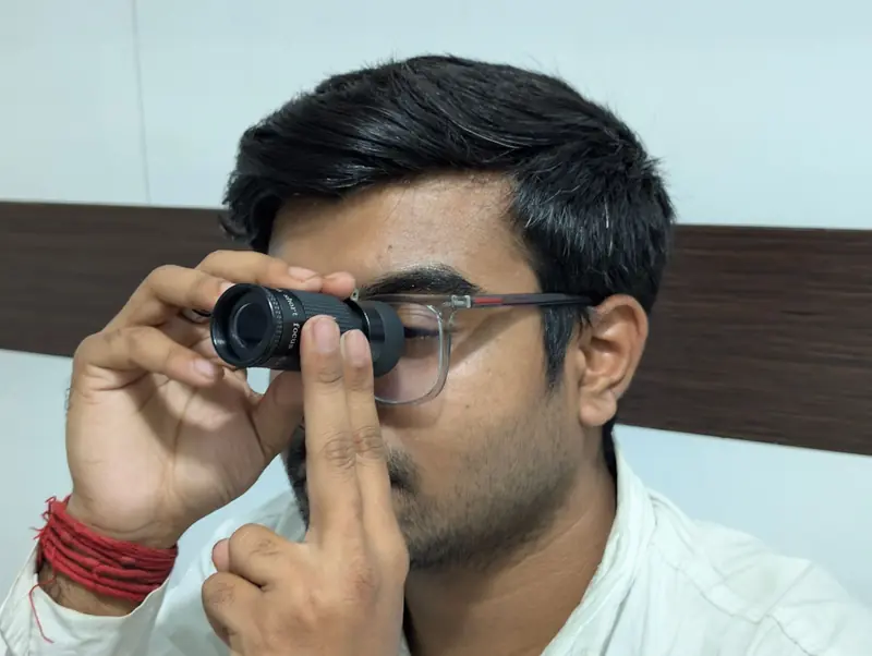 Portrait of man examining through a handheld telescope inside a room