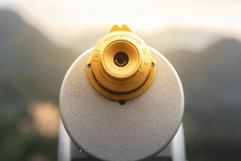 A close-up of a coin-operated telescope with a scenic blurred background
