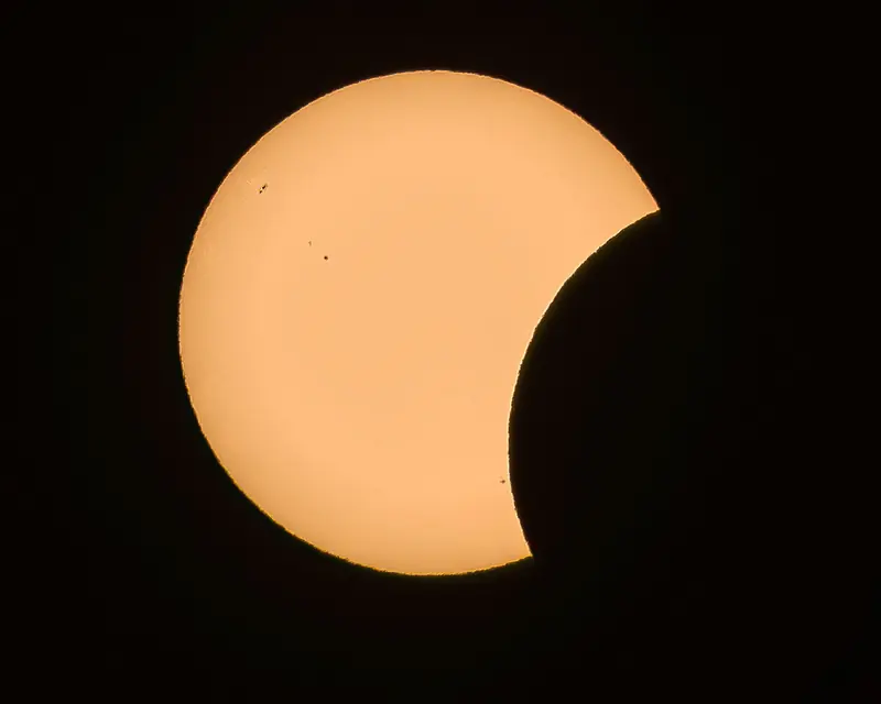 Close-up image of a partial solar eclipse with the moon casting a shadow on the sun